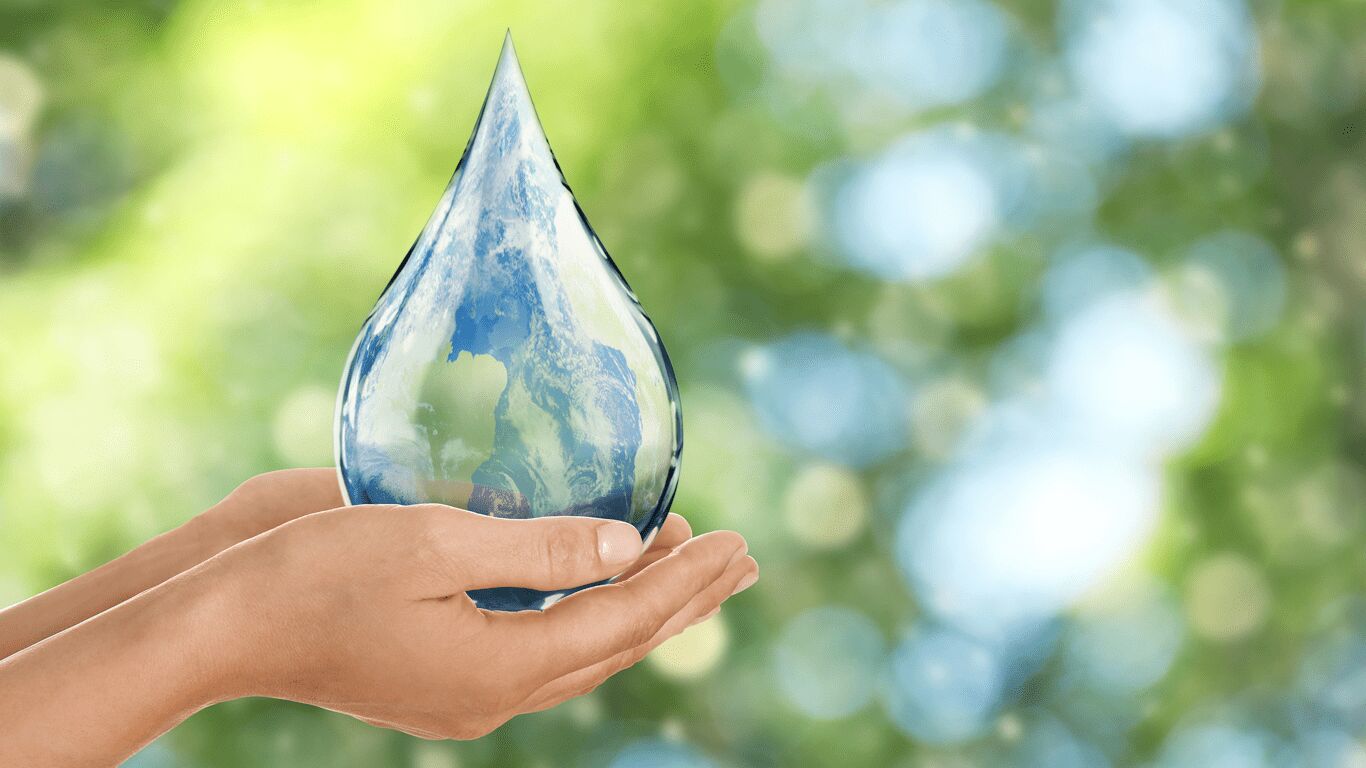 Hands cupped holding a water droplet, with blurry green and blue background. 